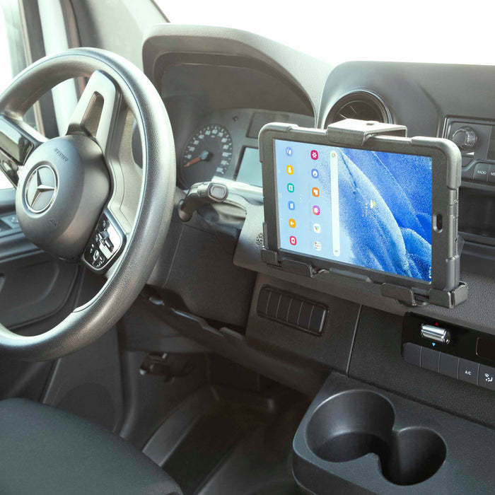 A Mercedes-Benz dashboard features a rugged-cased tablet, held securely beside the steering wheel by the LockVise™ Metal Locking Tablet Mount with Drill Base Mount, displaying a colorful home screen with app icons.