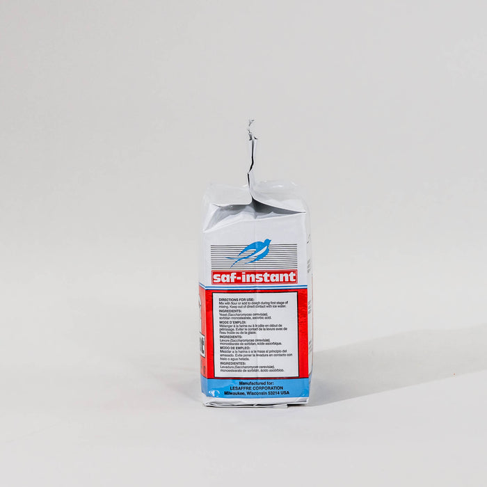 Side view of a single package of Saf Instant yeast on a grey background
