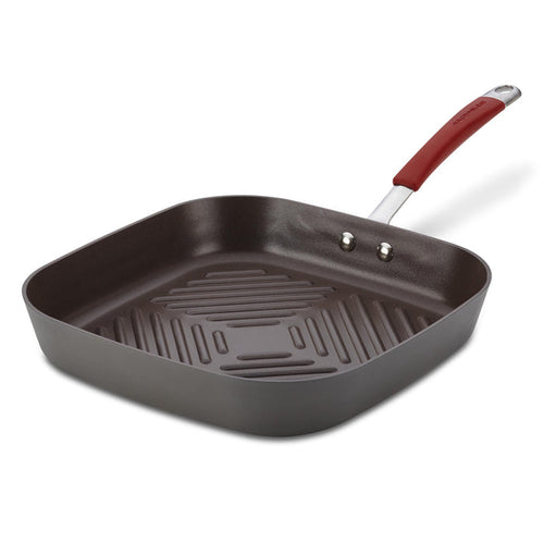 The 11-Inch Cucina Hard Anodized Nonstick Square Deep Grill Pan, featuring a red handle and ridged interior surface, is ideal for indoor grilling and offers oven-safe versatility.