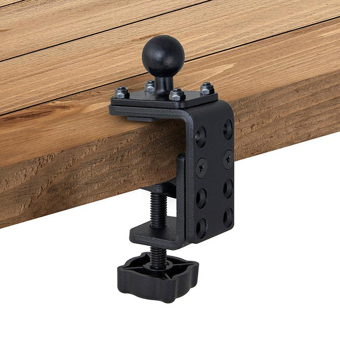 The 25mm (1 inch) Ball to Adjustable Clamp Adapter, featuring a black metal clamp base with a knob and ball mount, attaches to the edge of a wooden board. Compatible with Arkon Robust Series, it has a large threaded screw and multiple adjustment holes.