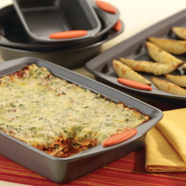 A casserole and pastries rest beautifully in the 5-Piece Nonstick Bakeware Set on a table with a napkin, ready to be baked to perfection. The heavy gauge steel ensures even heating, making every dish oven safe up to 500°F.