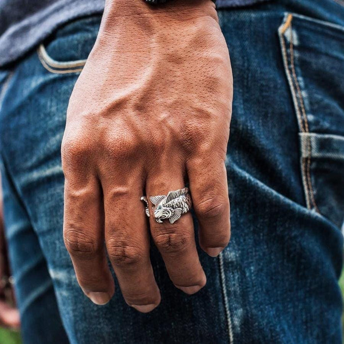 A man's finger wearing the detailed Japanese carp ring, showing its wrap-around design.