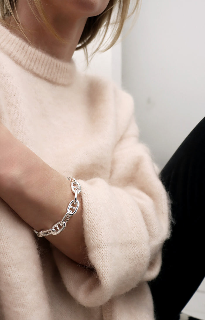 Kvinna som bär ett armband med silverkedja - modell ankarkedja. Ett chunky kedjearmband i äkta silver.