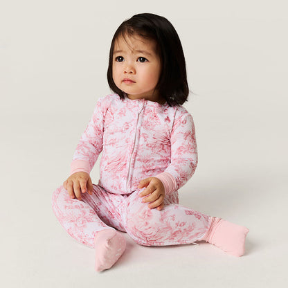 Child wearing a pink one piece outfit on a plain background