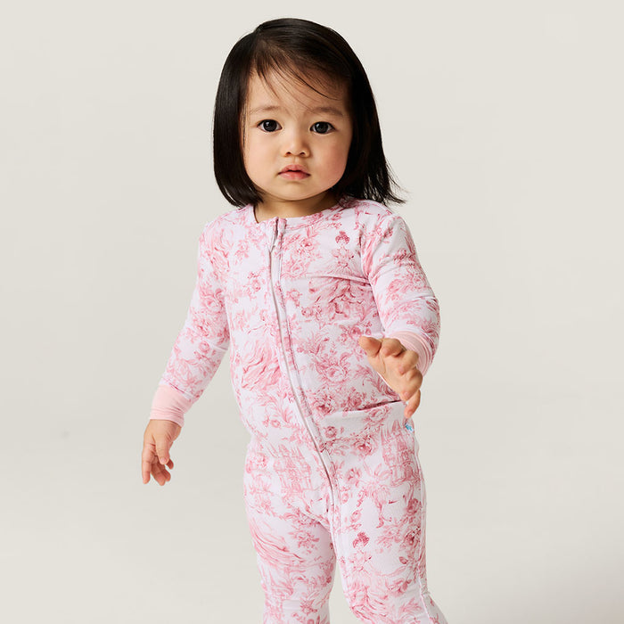 Child wearing a pink floral one piece against a plain background