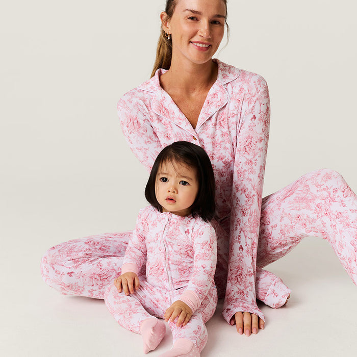Woman and child wearing matching pink floral pajamas on a light background