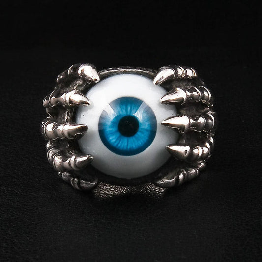 A sterling silver eyeball claw ring with a realistic blue eye held by a skeleton hand, shown on a black background.