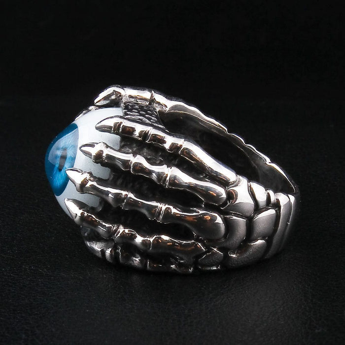 A close-up detail shot of the realistic eyeball ring, focusing on the sharp talons of the silver claw gripping the eye.