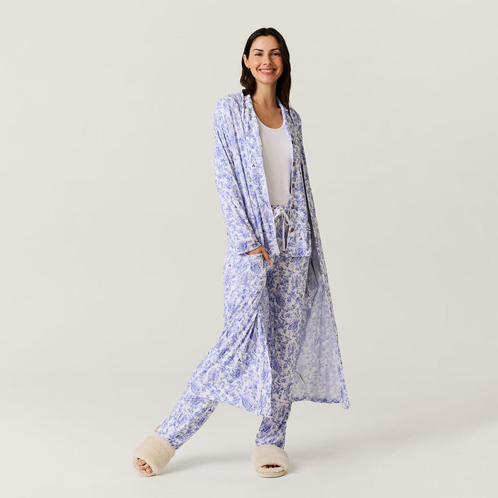 Woman wearing a long, light blue floral kimono-robe garment on a plain background