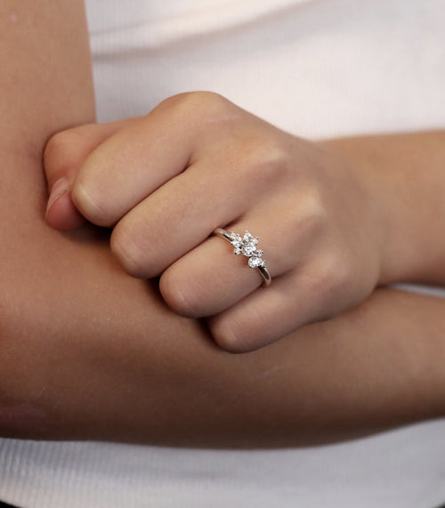 En tjej som bär en diamantring med flera diamanter i olika storlekar sammansatta som ett kluster.