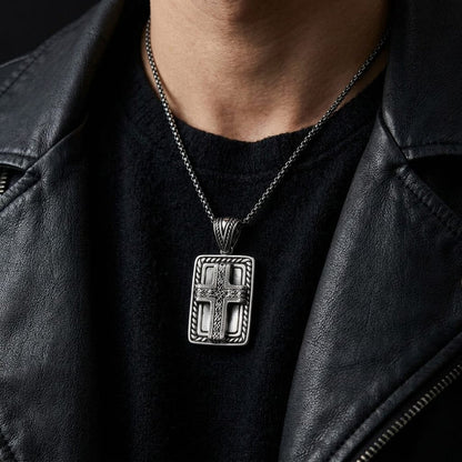 Close-up of a man wearing a silver Celtic knotwork cross pendant necklace over a black shirt and black leather biker jacket.