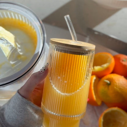 A woman holding a bottle of orange juice with a citrus juicer and oranges in the background