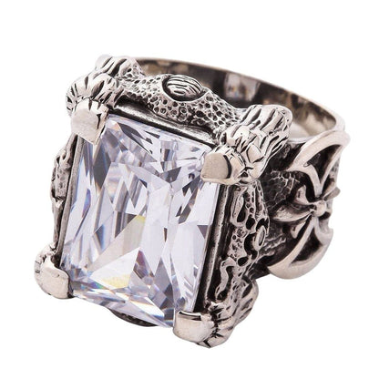 A close-up of the silver dragon talon ring, detailing the four powerful claws gripping the large, clear emerald-cut stone.