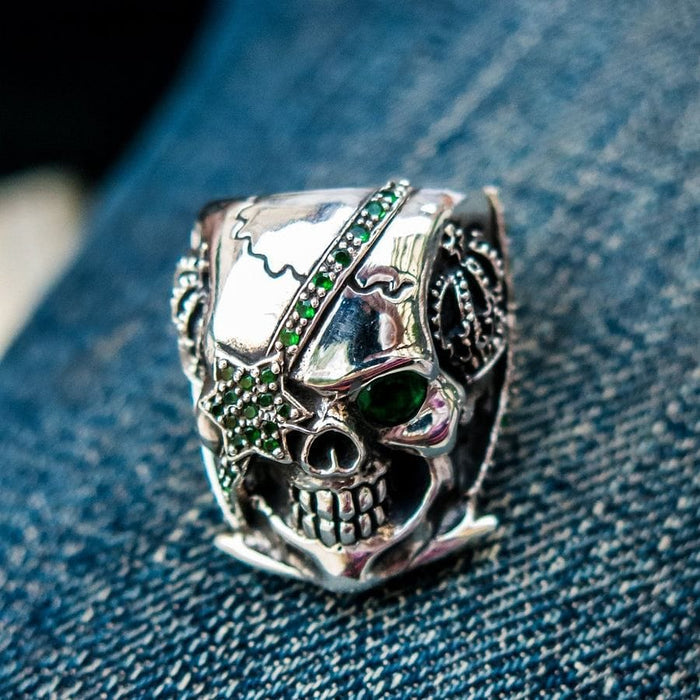 Angled view of the skull ring highlighting the emerald green star eye patch and crown detail.