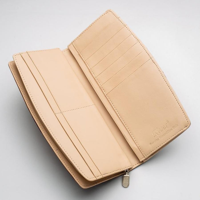 Open interior of a crocodile leather long wallet revealing beige card slots, bill compartments, and embossed brand logo with zipper pull
