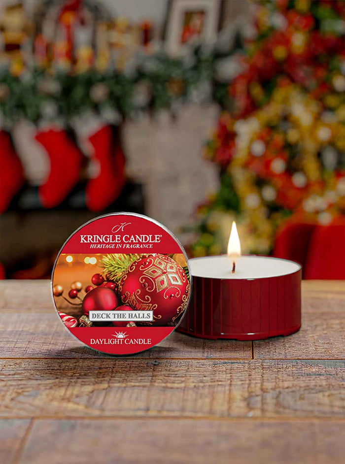 Kingle Candle 'Deck the Halls' daylight candle on a wooden surface with a festive background.