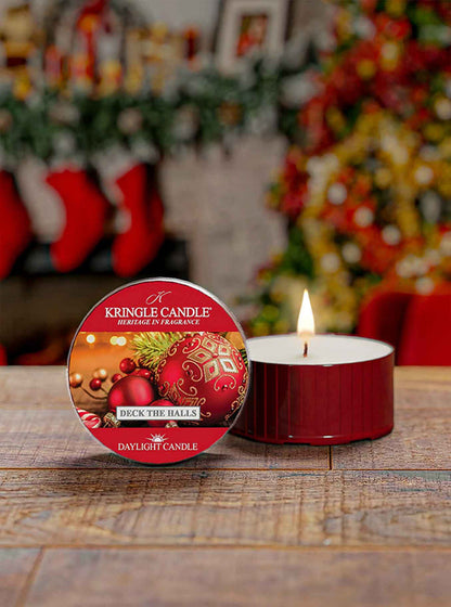 Kingle Candle 'Deck the Halls' daylight candle on a wooden surface with a festive background.