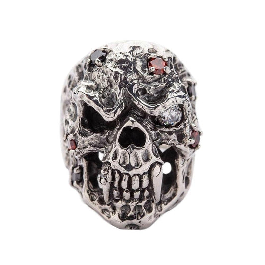 A heavyweight sterling silver skull vampire ring for men, featuring a rugged, corroded texture and gemstone eyes.