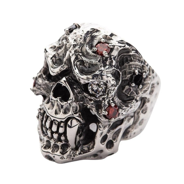A gothic vampire skull ring with sharp polished fangs and blood-red garnet accents.