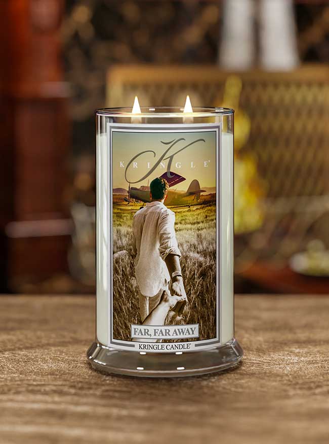 Kringle Candle with a label featuring a person in a field on a wooden surface.