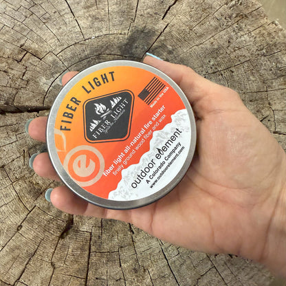 Hand holding a Fiber Light container against a wooden background