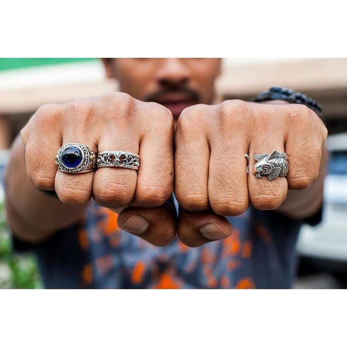 A man wearing the Fleur De Lis silver band ring alongside a gemstone ring on his fists.
