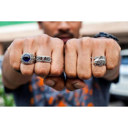 A man wearing the Fleur De Lis silver band ring alongside a gemstone ring on his fists.