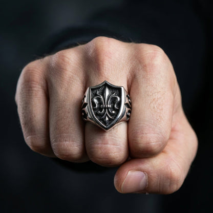 A man's hand wearing the large, heavy gothic fleur de lis ring, showing its scale.