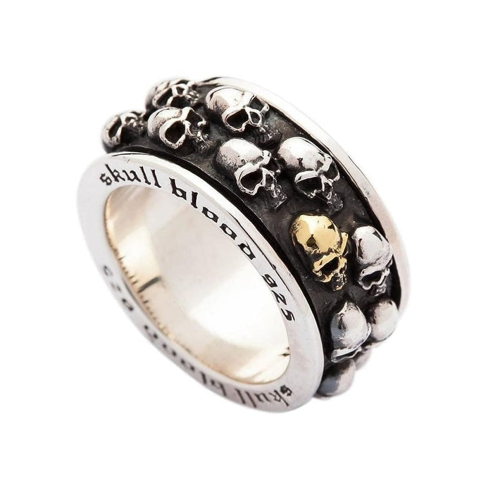 A sterling silver skull spinner ring with a gold skull accent, showing the engraved inner band.