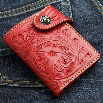 The tooled red leather wallet showing its intricate floral design on the denim background.