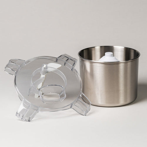White ice cream maker shown disassembled with its clear lid, paddle, and stainless steel bowl on a white background