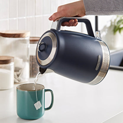 Person pouring tea from a blue electric kettle into a teal mug.