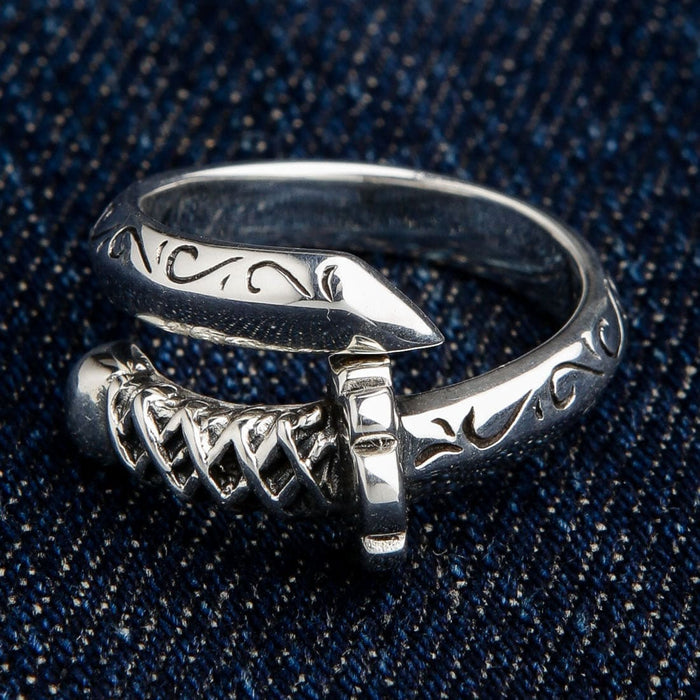 The Katana sword wrap ring on a dark denim background, highlighting the polished silver.