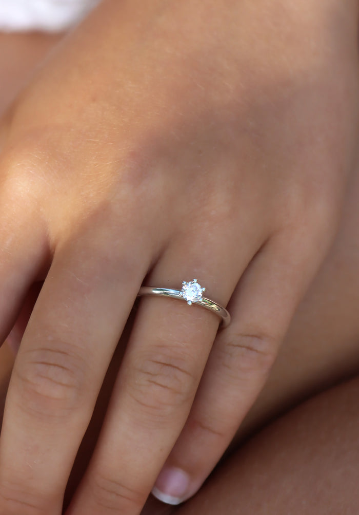 Tjej som bär en diamantring i silver med 0,25 ct rund diamant. Vigsel- eller förlovningsring.