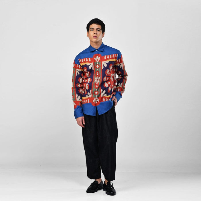 Man wearing the blue Kanaat shirt with black trousers, full length front view, one hand in pocket
