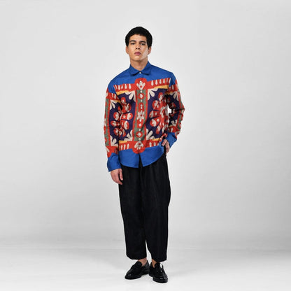 Man wearing the blue Kanaat shirt with black trousers, full length front view, one hand in pocket