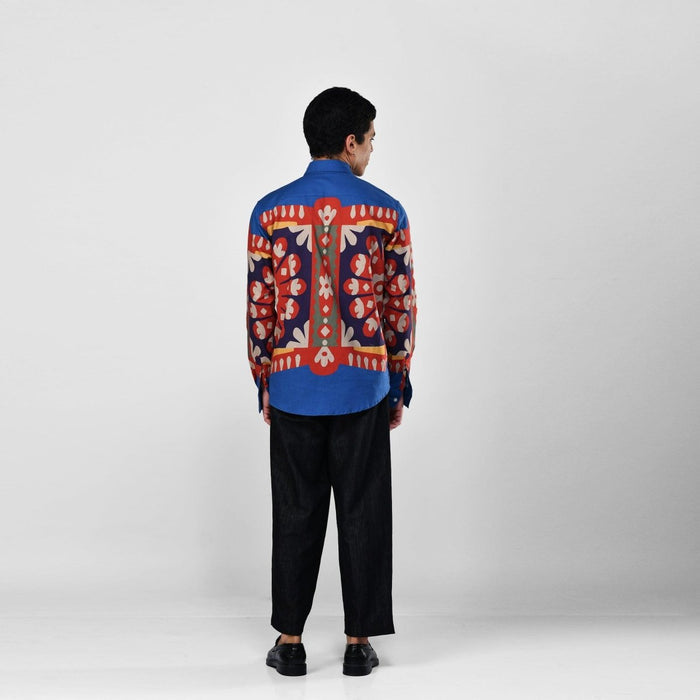 Man wearing the blue Kanaat shirt with black trousers, full length back view, with the pattern panel across the back