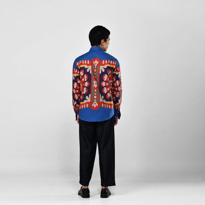 Man wearing the blue Kanaat shirt with black trousers, full length back view, with the pattern panel across the back