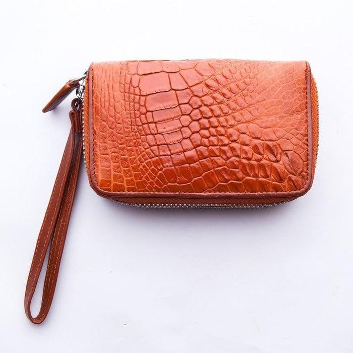 Top-down angle of brown crocodile leather wristlet wallet showing embossed scale texture and perimeter zip closure