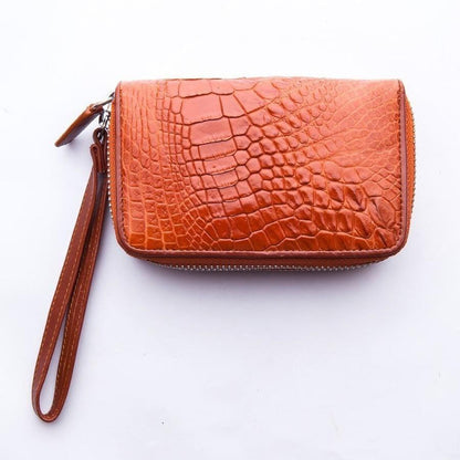 Top-down angle of brown crocodile leather wristlet wallet showing embossed scale texture and perimeter zip closure