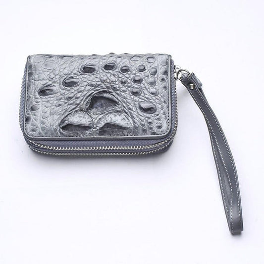 Light gray genuine crocodile leather zip-around wallet with raised horn-back scales and wrist strap on white background