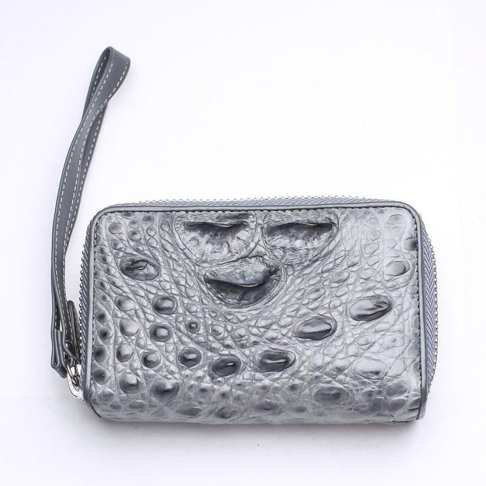 Compact gray crocodile leather wristlet wallet showing natural hornback texture and attached leather strap on white surface