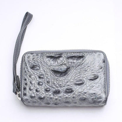 Compact gray crocodile leather wristlet wallet showing natural hornback texture and attached leather strap on white surface
