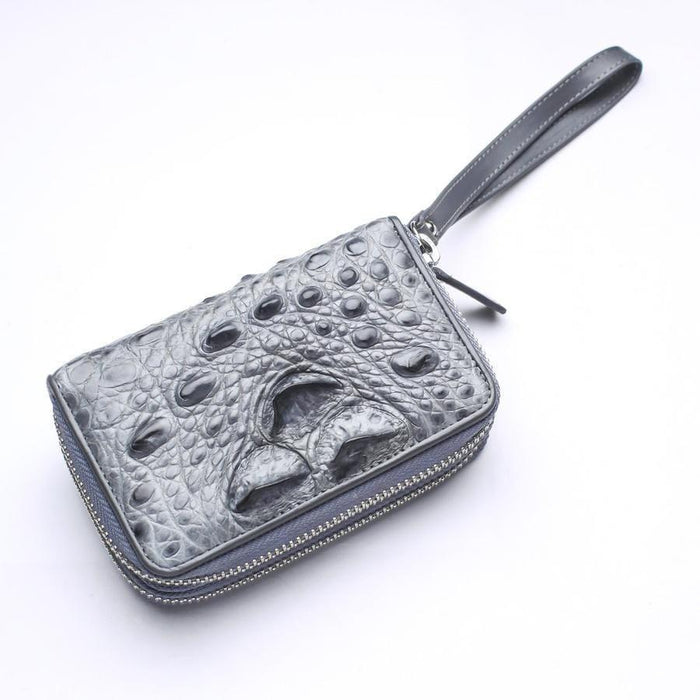 Angled view of gray crocodile wristlet wallet highlighting raised hornback crown scales and silver-tone zip-around closure