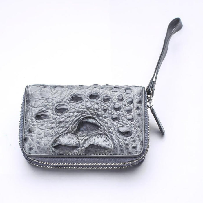 Overhead angled shot of gray crocodile leather zip wallet showcasing raised bumpy hornback scales and leather wrist loop