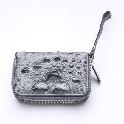 Overhead angled shot of gray crocodile leather zip wallet showcasing raised bumpy hornback scales and leather wrist loop
