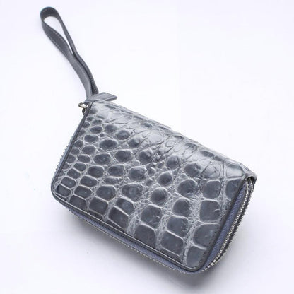 Perspective view of gray crocodile leather wristlet showing natural scale size gradient from small edge tiles to large center bumps