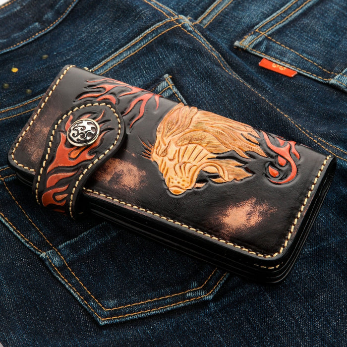 Lifestyle shot of the lion carved wallet placed on blue denim jeans, highlighting the biker aesthetic.