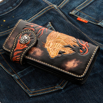 Lifestyle shot of the lion carved wallet placed on blue denim jeans, highlighting the biker aesthetic.