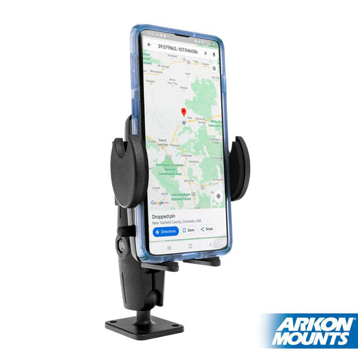 A smartphone showing a map with a pin is held in a Drill-Base Mega Grip™ Phone Mount for iPhone, Galaxy, Note, and more by Arkon Mounts, featuring an adjustable arm and the Arkon Mounts logo at the bottom right.